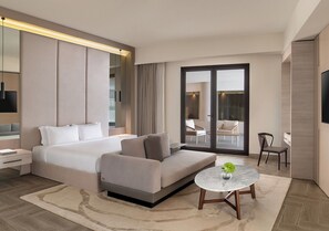 A modern hotel room with a bed, sofa, round table, and a view through a glass door.