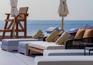 Una piscina al aire libre, sombrillas, sillones reclinables de piscina
