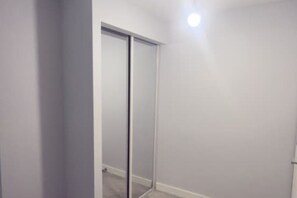 Ein Zimmer mit Schiebetür, einer Deckenleuchte und einer schlichten Wand.