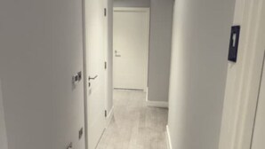 A narrow hallway with a door at the end, a light switch, and a wall-mounted light fixture. - 2 Bedroom - Rubix (London)