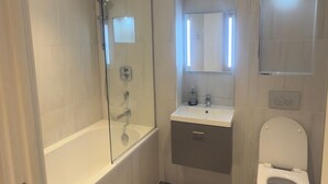 A bathroom with a glass-enclosed shower, a sink with a mirror above it, and a toilet. - 2 Bedroom - Rubix (London)