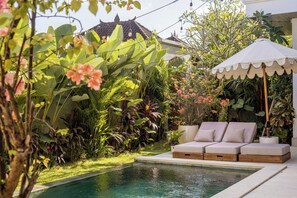 Una piscina al aire libre, sillones reclinables de piscina