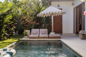 Una piscina al aire libre, sillones reclinables de piscina