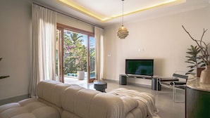 Una sala de estar moderna con un sofá, televisor y una planta.