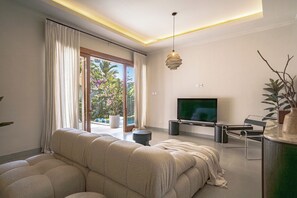 Ein modernes Wohnzimmer mit einer Couch, einem Fernseher und einer Pflanze.