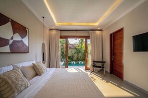 Ein Schlafzimmer mit einem Bett, einem Fernseher, einem Schreibtisch und Blick auf einen Außenpool.