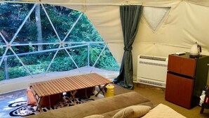 Une pièce aménagée avec une tente, un lit, une petite table, un radiateur et un placard.
