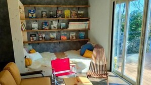 Un salon moderne avec un canapé, une table basse en bois, un fauteuil rouge et une bibliothèque remplie de livres.