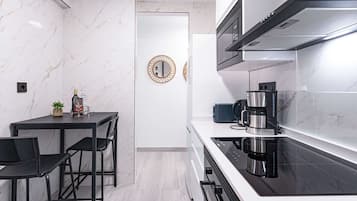 Eine moderne Küche mit schwarzem Arbeitsplatz, Edelstahlgeräten und einer Marmor-Spritzschutzwand.