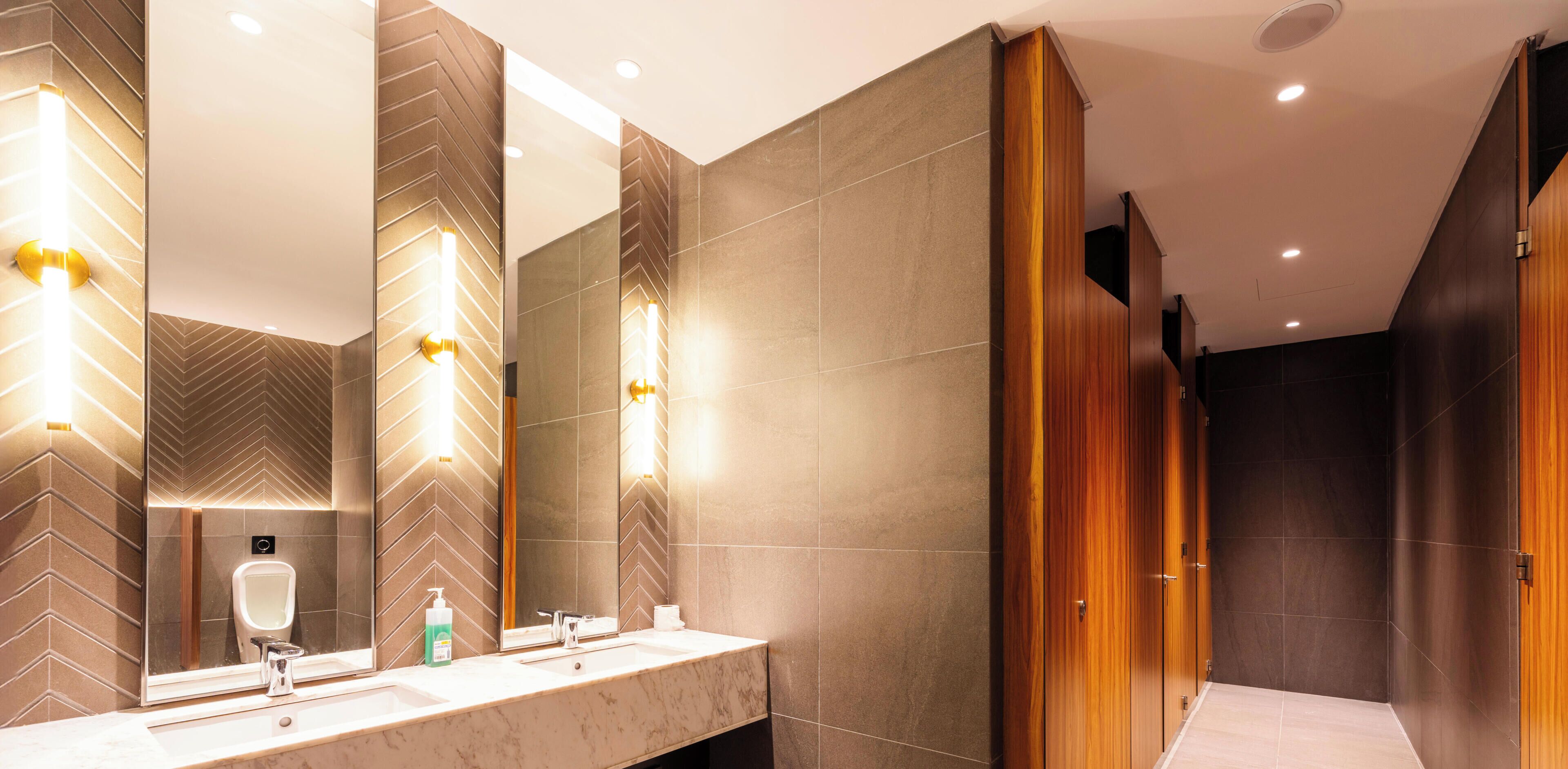 A modern bathroom with a large mirror, two sinks, and a wooden wardrobe.