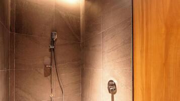 A shower with a handheld showerhead and a wall-mounted control panel.