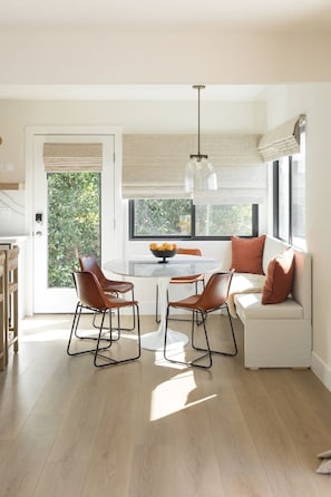 A modern kitchen with a dining area, large windows, and a hanging light fixture. - The SouthOhana Beach House with Ocean Views! (Oceanside)