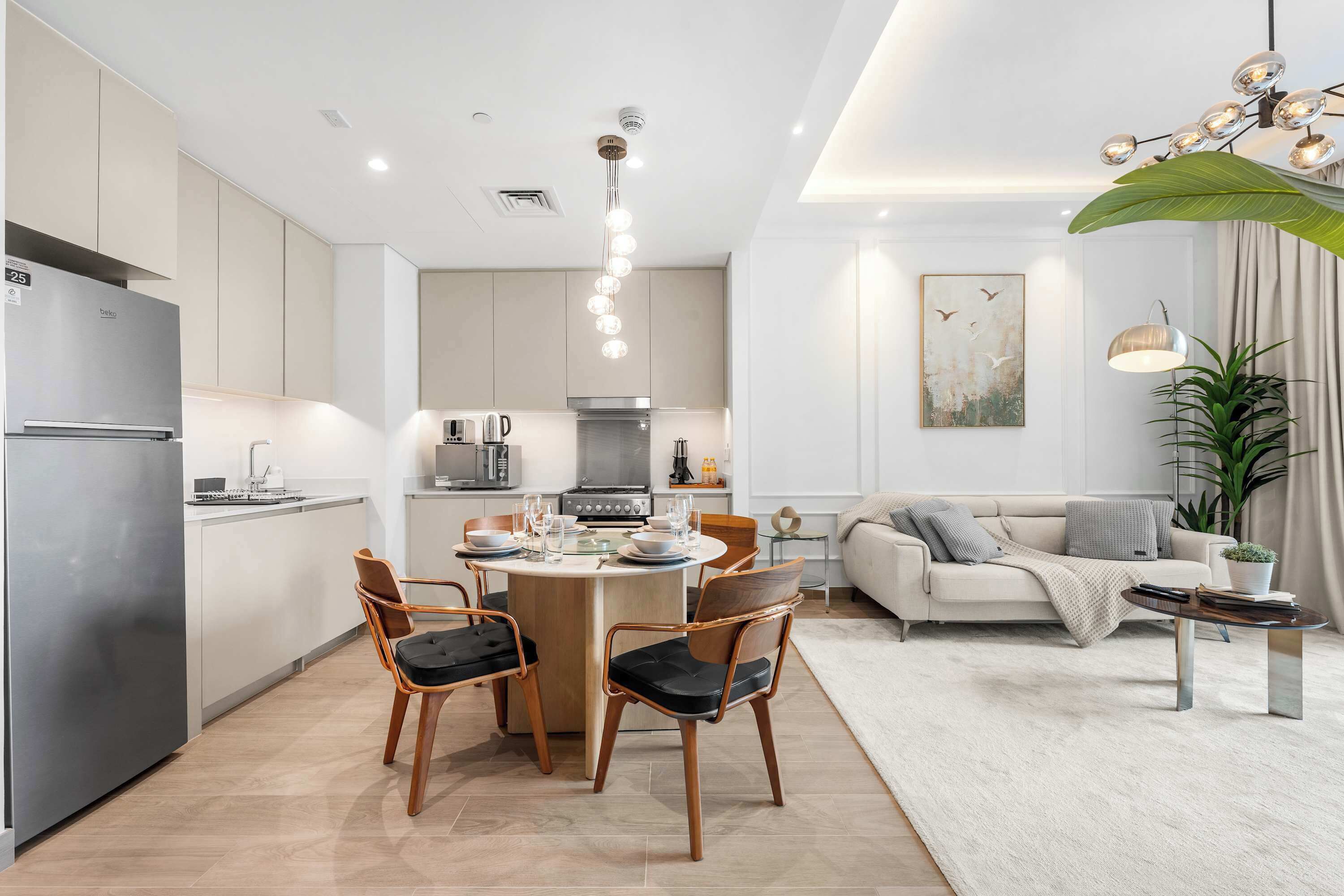 Une cuisine moderne avec un îlot central, un coin repas avec des chaises, un canapé et une table basse.