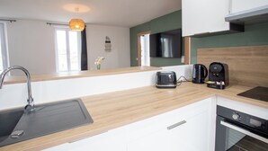 Une cuisine moderne dotée d’un plan de travail en bois, d’un évier encastré, d’une machine à café et d’un lave-vaisselle.