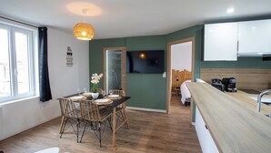 Une cuisine moderne avec un plan de travail en bois, un coin repas avec des chaises en osier et une grande fenêtre avec des rideaux.