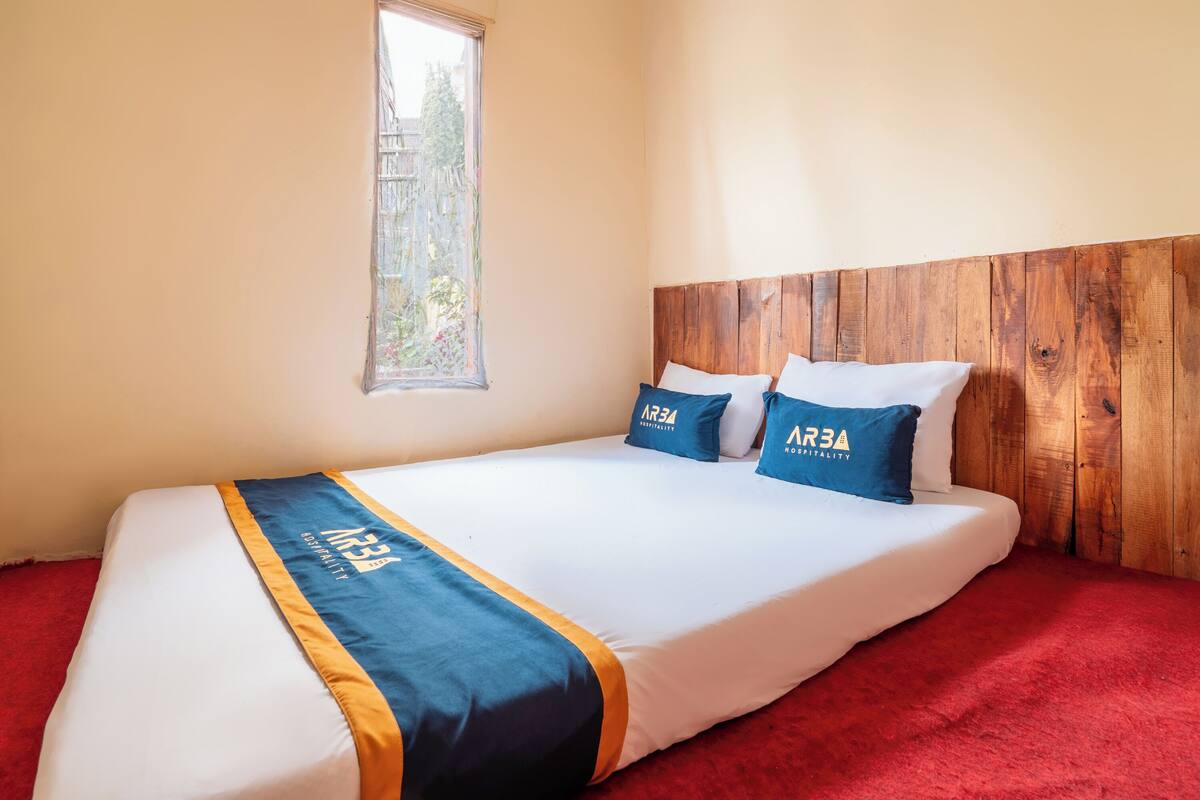 Una habitación de hotel con una cama, una ventana y un cabecero de madera.