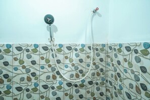 A shower with a leaf-patterned tile wall.