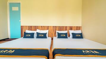 A hotel room with two beds, each with a matching pillow and bedspread featuring the hotel's logo.