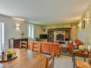 Ein Wohnzimmer mit Kamin, Esstisch und gemütlichen Sitzgelegenheiten.