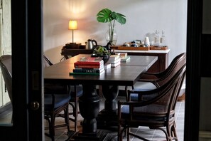Un espace repas comprenant une table, des chaises, une lampe, une plante et divers objets disposés sur la table.