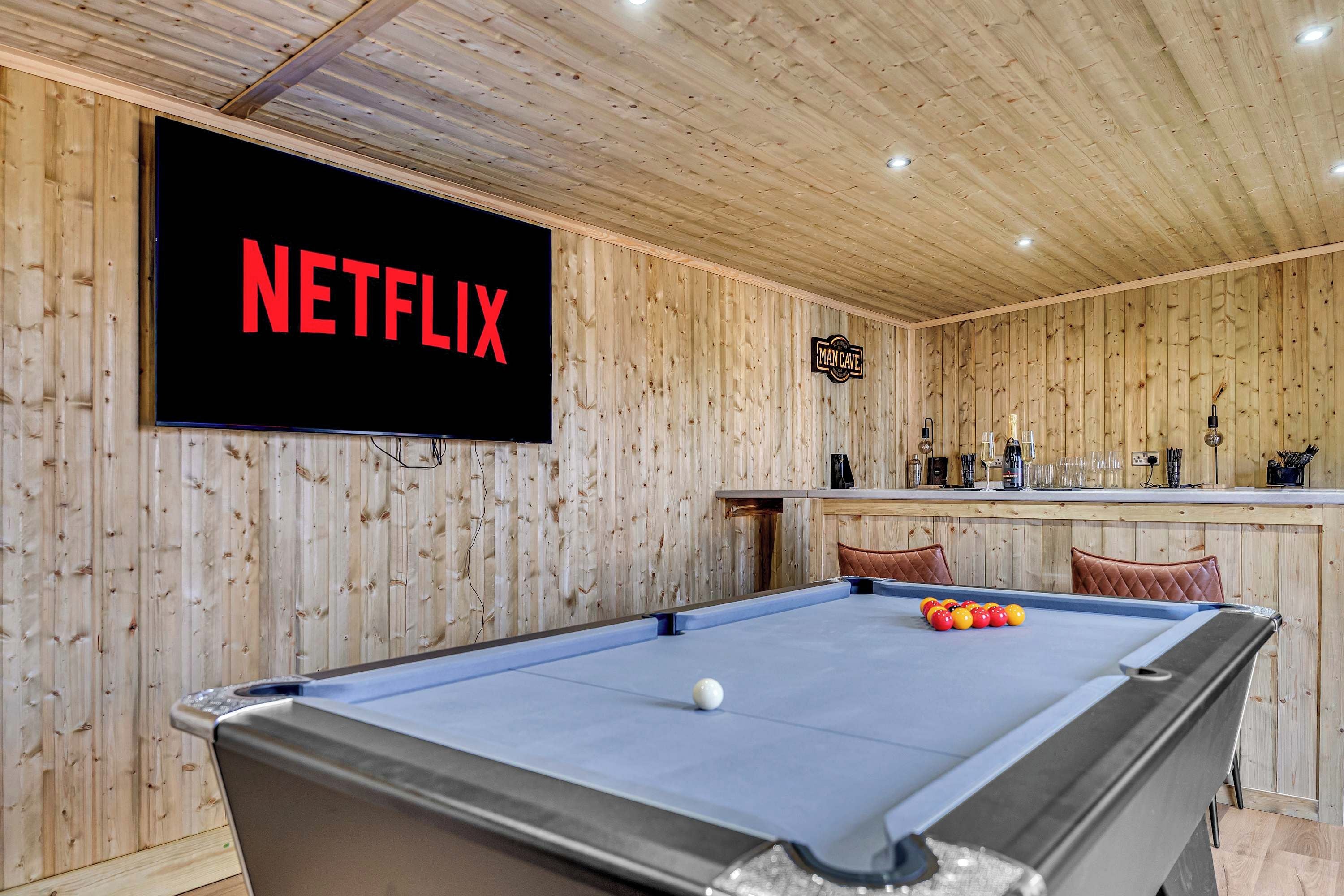 A pool table with a billiard cue, a pool ball, and a sign reading 'NETFLIX' on the wall.