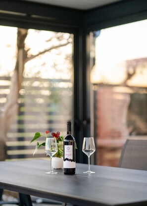 A table with a wine bottle and two glasses, a potted plant, and a view through a window. - Holiday Home Tanja Vir with heated pool (Vir)