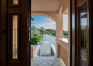 An entrance with a tiled pathway leading to a covered area with a view of the sky and greenery. - Holiday Home Tanja Vir with heated pool (Vir)