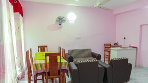 Una habitación con una mesa de comedor, sillas, un sofá, un ventilador y un escritorio con una silla.