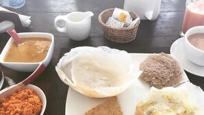 Una mesa con un plato de comida, una taza de té, una jarra de agua y una cesta con una bolsita de té.