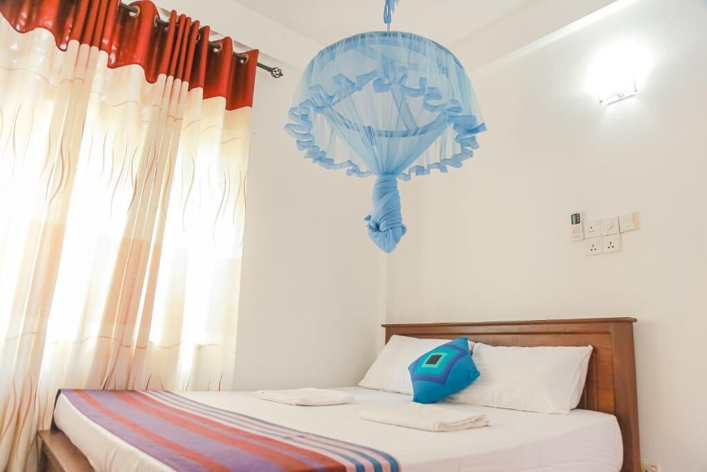A bedroom with a bed, a canopy, and a window with curtains.