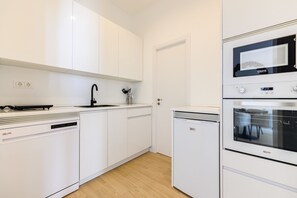 Eine moderne Küche mit weißen Schränken, einem Geschirrspüler, einem Kühlschrank und einem Backofen.