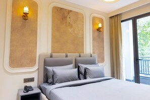 Hotellihuone, jossa on suuri sänky, kaksi seinävalaisinta, puhelin yöpöydällä ja näkymä vehreään maisemaan.
