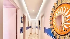A hotel hallway with a patterned floor, a decorative mirror, and a door at the end. - Hostdomus - Villino Matilde (Finale Ligure)