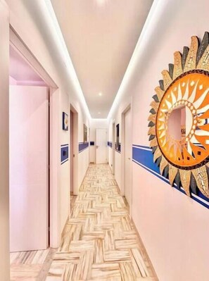 Een hotelgang met een patroon vloer, een decoratieve spiegel en een deur aan het einde.