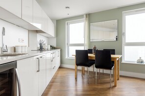 Eine moderne Küche mit weißen Schränken, einem Holzespeisetisch und schwarzen Stühlen.