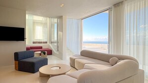 Una sala de estar moderna con un sofá modular grande, una mesa de centro redonda y un televisor de pantalla plana montado en la pared.