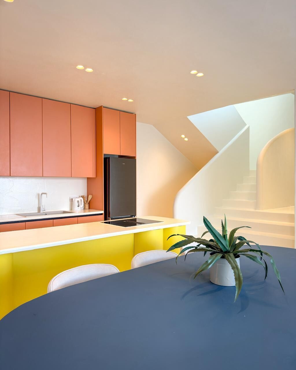 A modern kitchen with a built-in oven, a sink, and a dining area with a table and chairs.