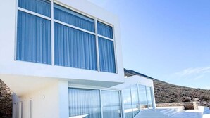 Una casa moderna con piscina, ventanas amplias y un muro de piedra.