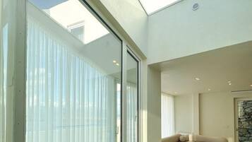 A modern interior with a large glass window, a sectional sofa, and a round table.