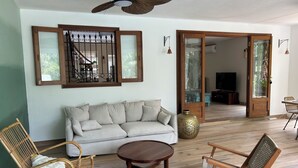 Ein Wohnzimmer mit einer Couch, zwei Korbstühlen, einem Couchtisch, einem Deckenventilator und einer großen Vase.