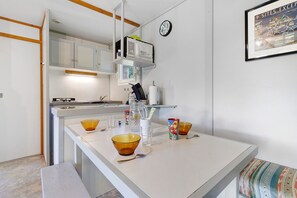 Eine moderne Küche mit weißen Schränken, einer eingebauten Mikrowelle und einer kleinen Kochinsel mit Schüsseln und Tassen.