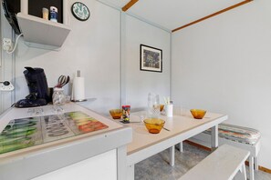 Eine Küchenzeile mit weißer Arbeitsplatte, einer Kaffeemaschine, Schüsseln und einem gerahmten Bild an der Wand.