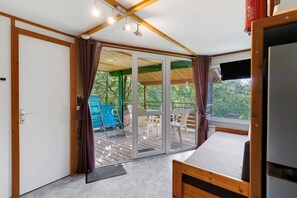 Ein Zimmer mit einem Bett, einer Glasschiebetür zu einem Außenbereich mit Stühlen und einer blauen Konstruktion.