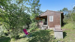 Eine rustikale Holzhütte mit Veranda, umgeben von Bäumen und Gras.