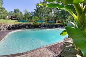 A clear pool with a wooden deck, stone walls, and green umbrellas. - Chalet 2 at Laupié near Sarlat (Proissans)
