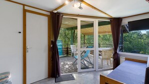 Ein Zimmer mit einem Bett, einer Schiebetür zu einer Terrasse und einer Decke mit sichtbaren Holzbalken.