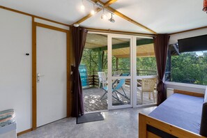 A room with a bed, a sliding glass door to an outdoor deck, and a ceiling with exposed beams. - Chalet 2 at Laupié near Sarlat (Proissans)