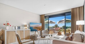 Ein modernes Hotelzimmer mit großem Balkon, einem Flachbildfernseher, einer Couch und einem Essbereich.