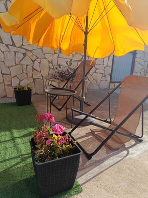 Un espace patio agrémenté d’un mur en pierre, de mobilier d’extérieur et de plantes en pot.