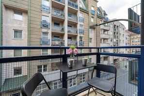 Un balcon avec une table, des chaises et un vase rempli de fleurs.